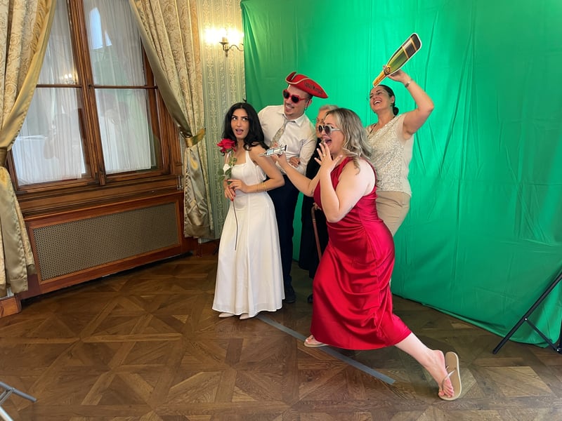 Gäste in festlicher Kleidung albern mit Requisiten am Greenscreen