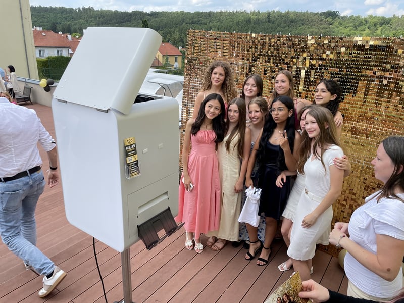 Gruppe von Absolventinnen an einer goldenen Glitzerwand mit Fotobox